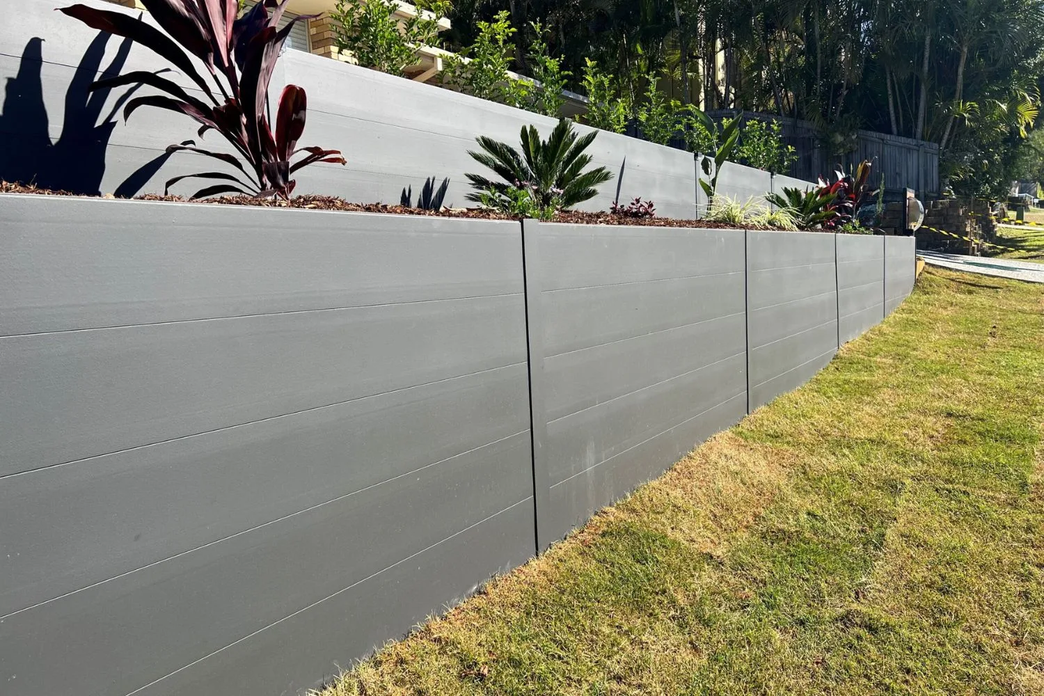 Dark grey concrete block retaining wall in a residential backyard