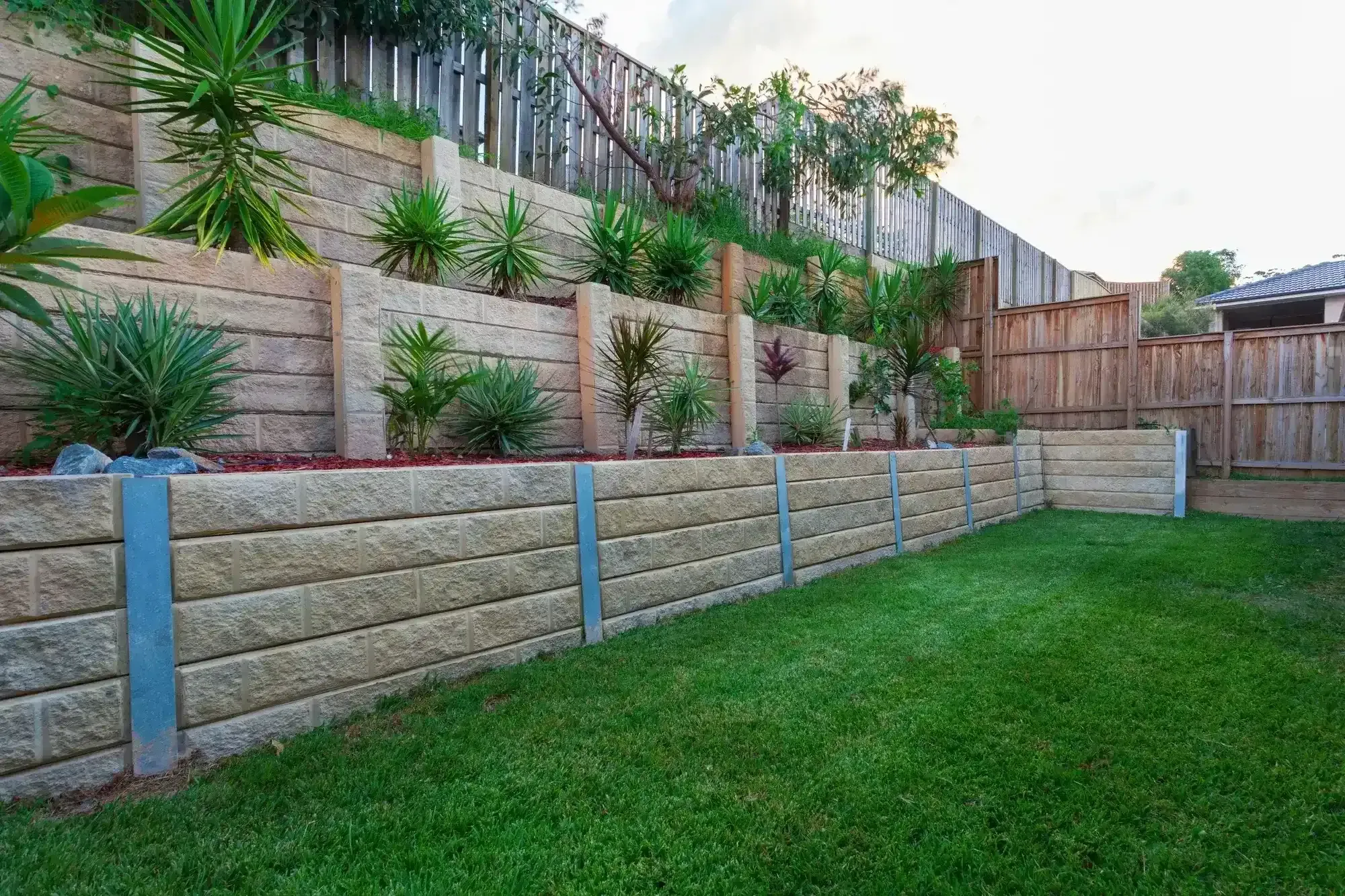 Concrete edged garden bed retaining wall along a fence line