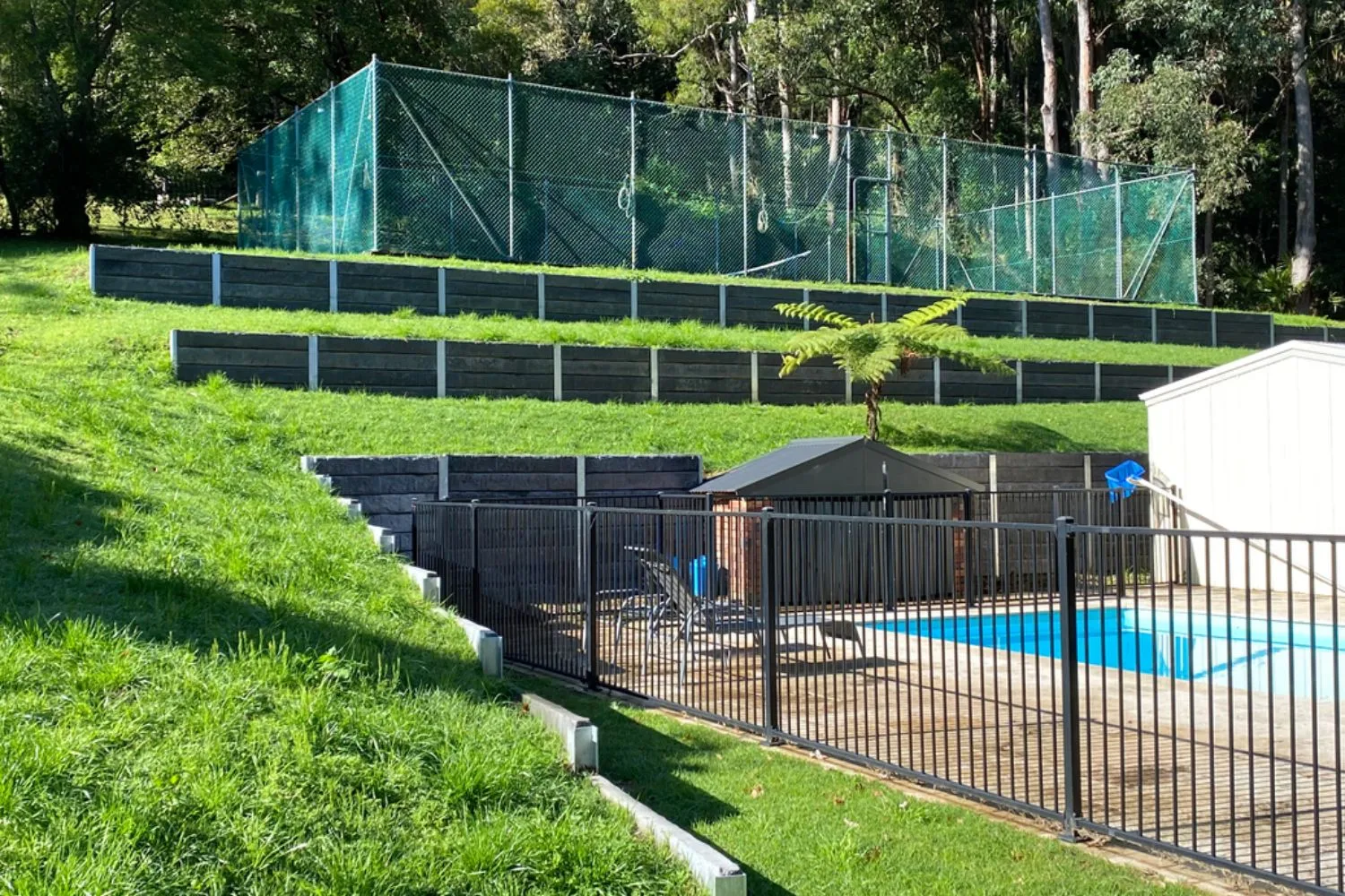 Tiered concrete sleeper retaining walls beside a backyard pool