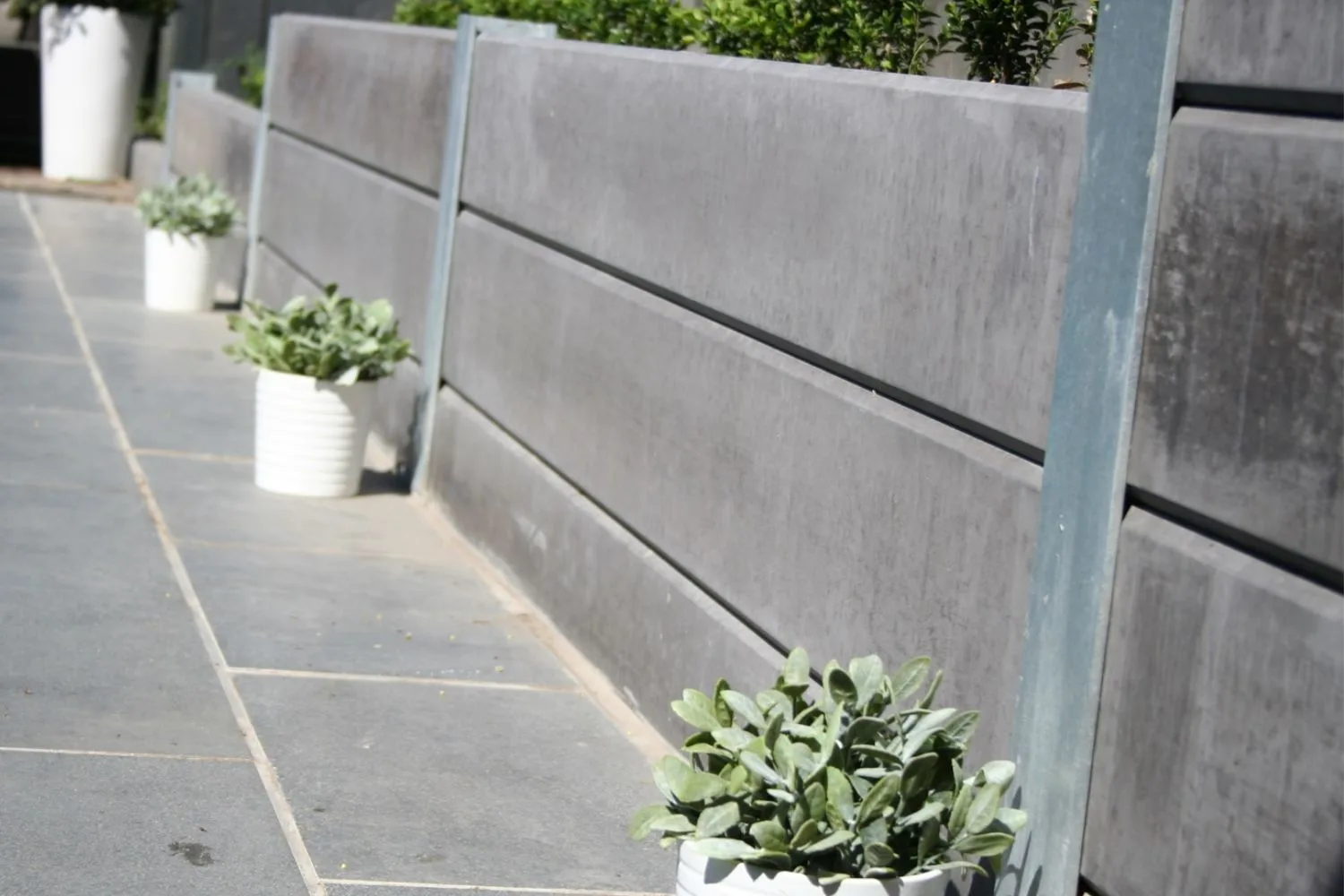 Concrete sleeper retaining wall with potted plants along a courtyard