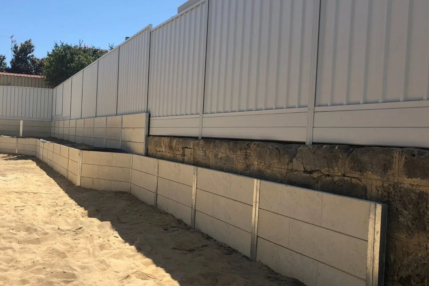 Concrete sleeper boundary retaining wall along a curved residential street