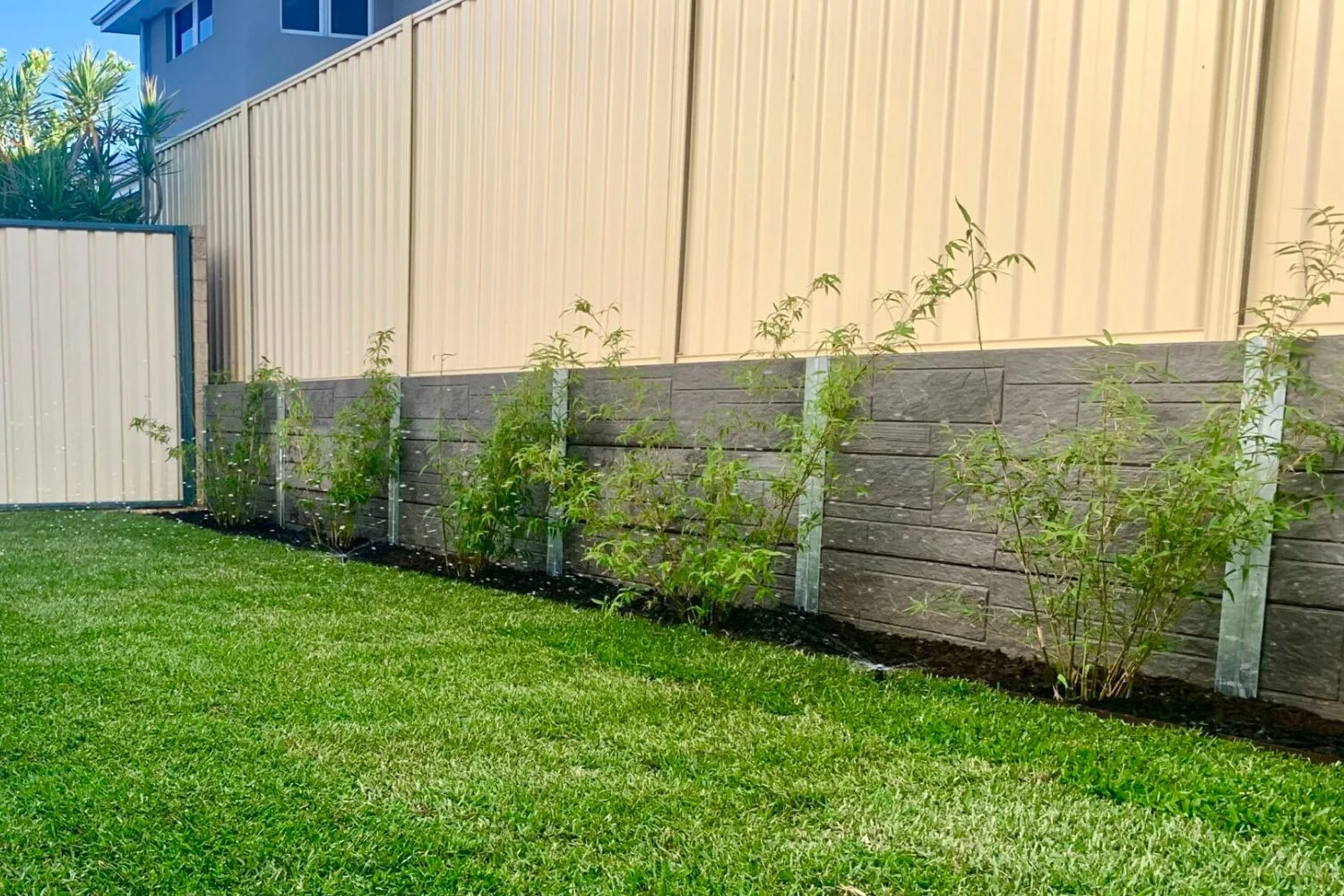 Concrete sleeper retaining wall beside a bamboo garden bed and fence