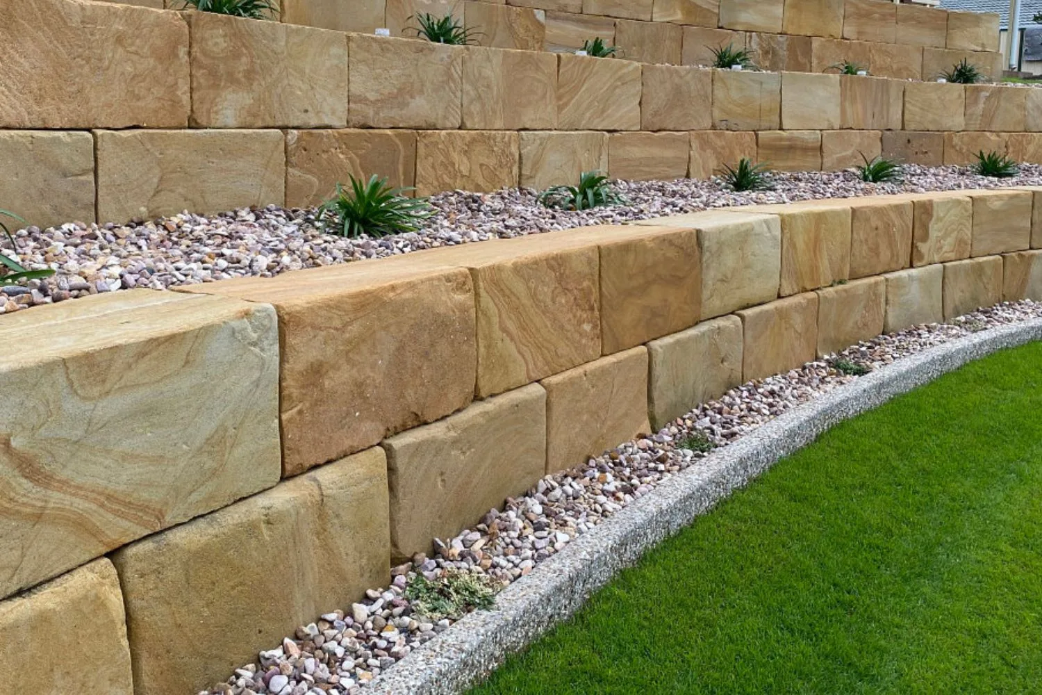 Tiered sandstone block retaining walls with pebble garden beds