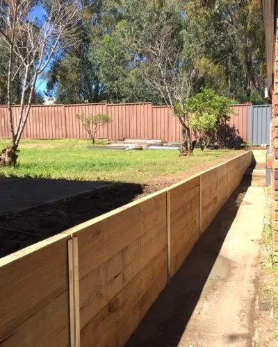 Treated pine timber retaining wall along a backyard lawn