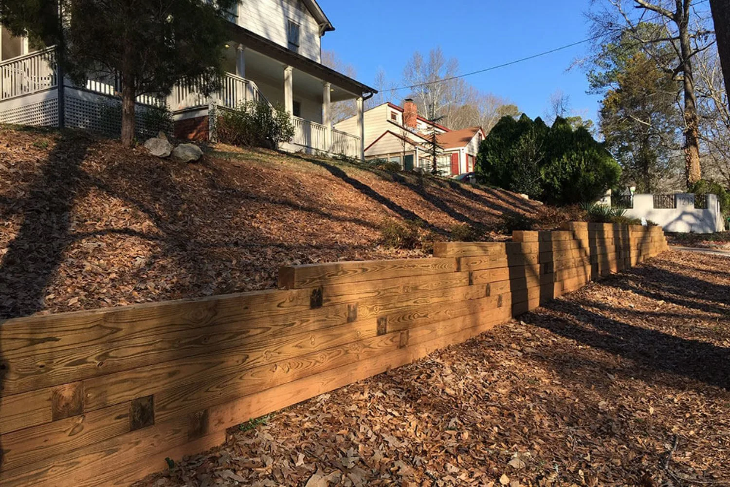 Timber retaining wall with steel posts beside sandstone boulders