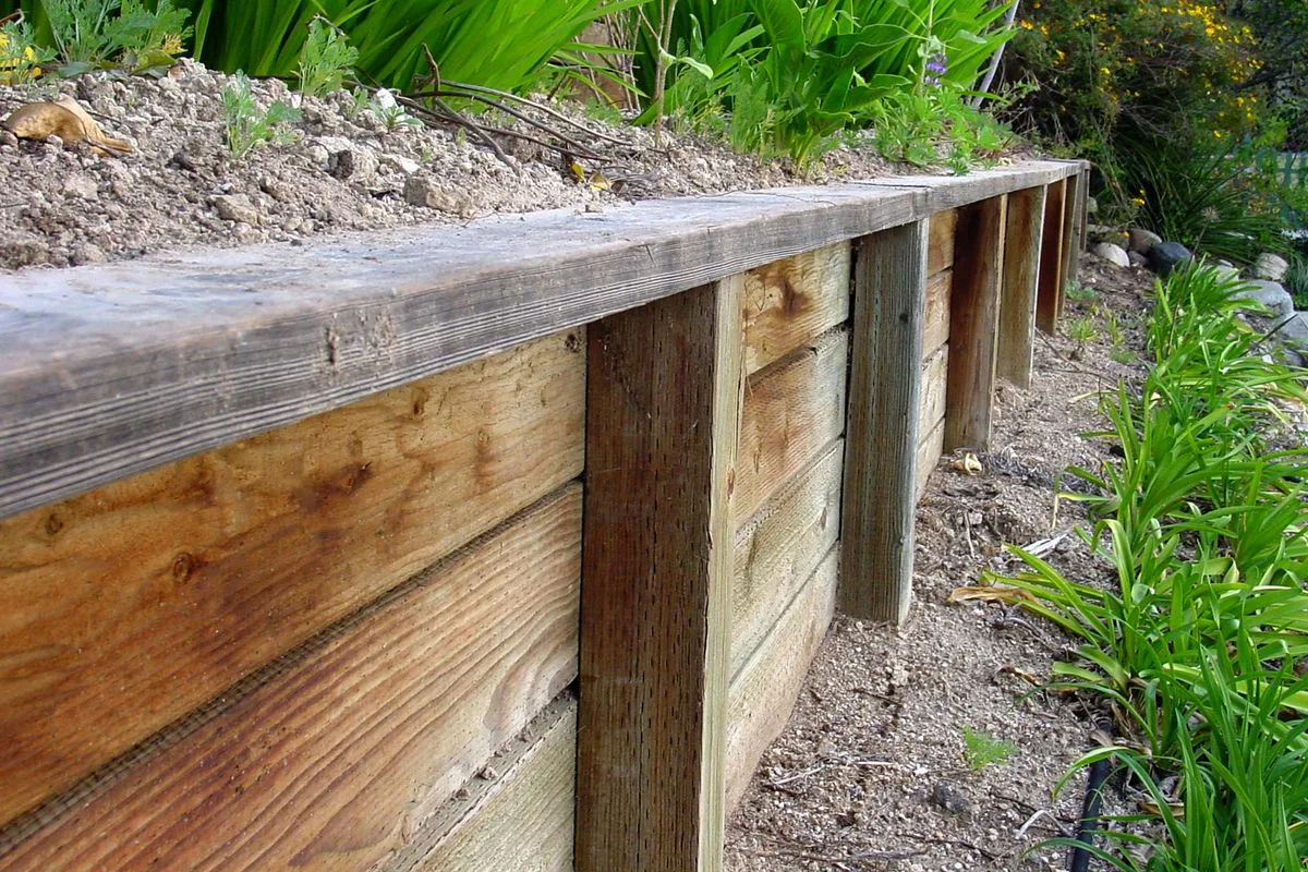Corner timber retaining wall bed with mulch and new plantings