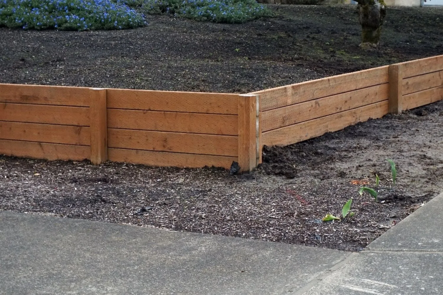 Treated pine retaining wall with steel posts beside garden mulch